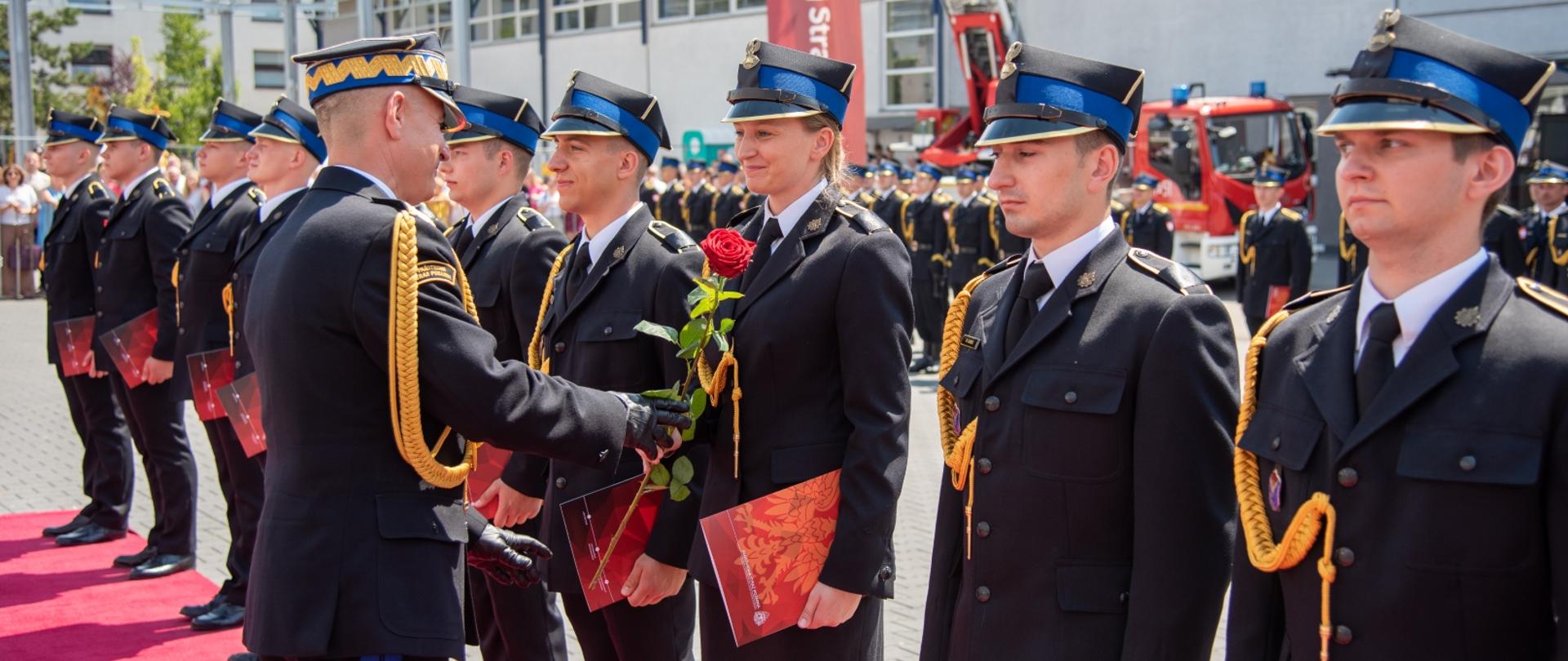Na zdjęciu widać jak komendant główny PSP wręcza kwiat nowo promowanej 
