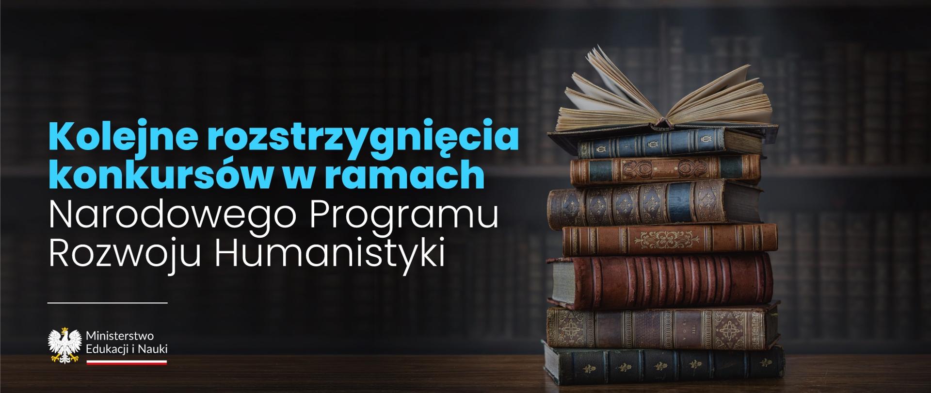 Grafika - Na drewnianym blacie leży stos starych książek, i napis Kolejne rozstrzygnięcia konkursów w ramach Narodowego Programu Rozwoju Humanistyki.