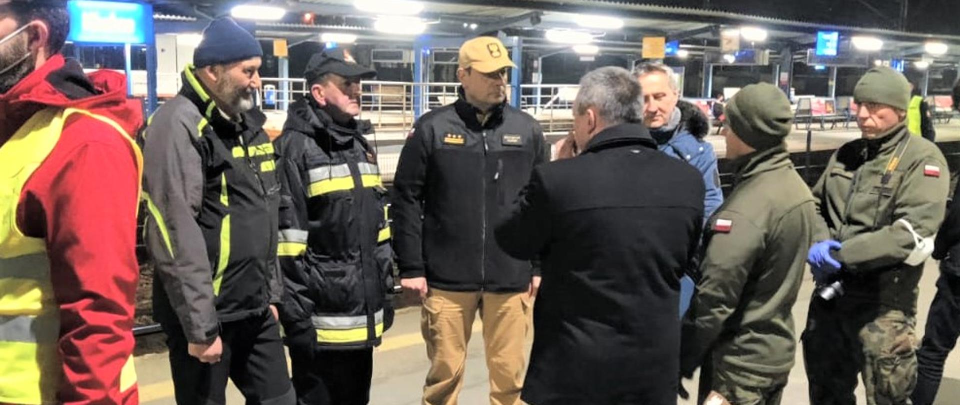Na zdjęciu przedstawiono dworzec kolejowy w Kielcach. Na pierwszym planie kilka osób m. in.: wojewoda świętokrzyski Zbigniew Koniusz z pracownikami oraz przedstawiciel Urzędu Miasta Kielce, świętokrzyski komendant wojewódzki Państwowej Straży Pożarnej st. bryg. Krzysztof Ciosek i komendant miejski PSP st. bryg. Sławomir Karwat. W tle perony kolejowe.