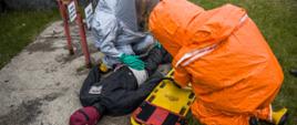 Ratownicy zabezpieczeni w ubrania gazoszczelne ochrony chemicznej ewakuują poszkodowanego pracownika zakładu. 