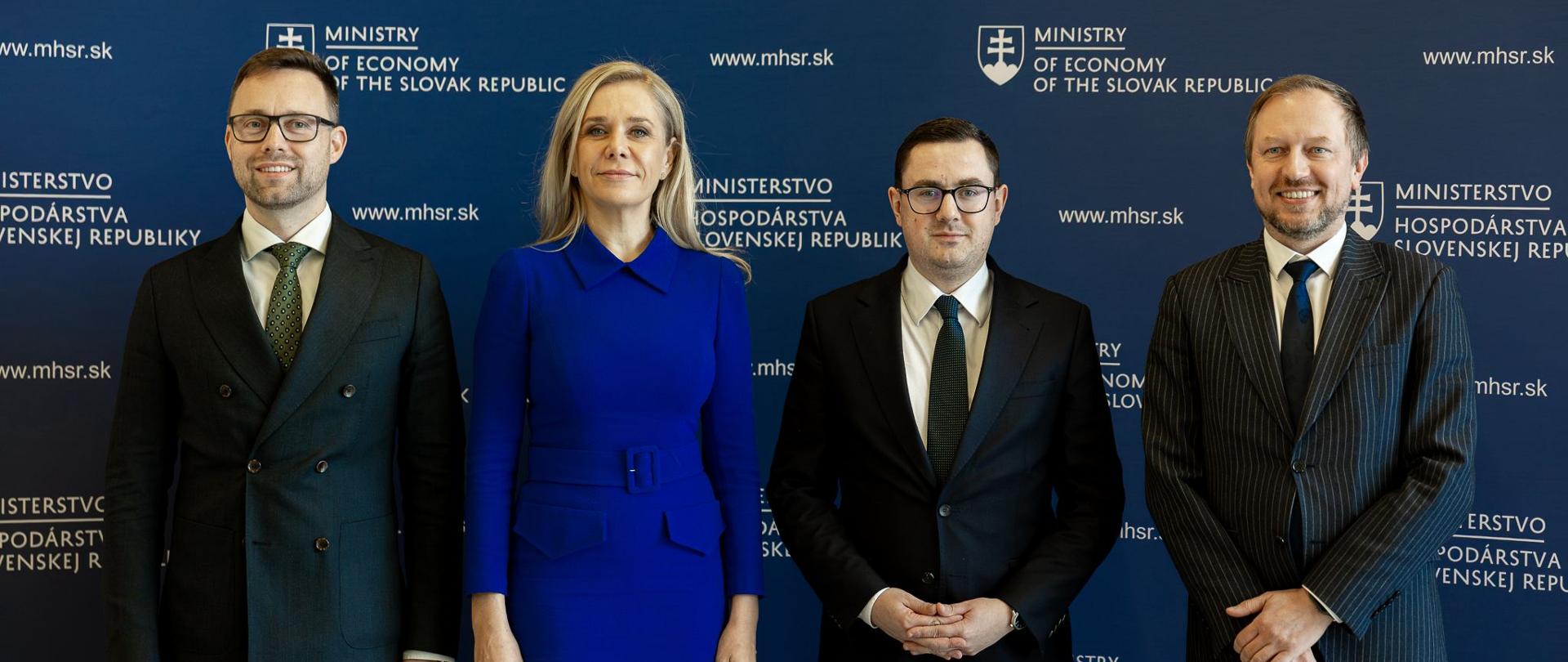 Szabolcs Hodosy, Denisa Saková, Miłosz Motyka i Wojciech Wrochna pozują do zdjęcia na tle granatowej ścianki z logotypami słowackiego Ministerstwa Gospodarki podczas wizyty w Bratysławie.