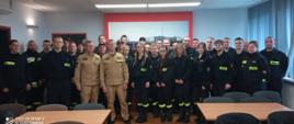 Strażacy stoją w kilku rzędach pozując do grupowego zdjęcia.