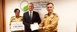Zastępca Komendanta Wojewódzkiego PSP w Warszawie, Główna Księgowa PSP w Warszawie oraz Dyrektor WFOŚiGW w Warszawie prezentują podpisaną umowę na tle loga funduszu. 