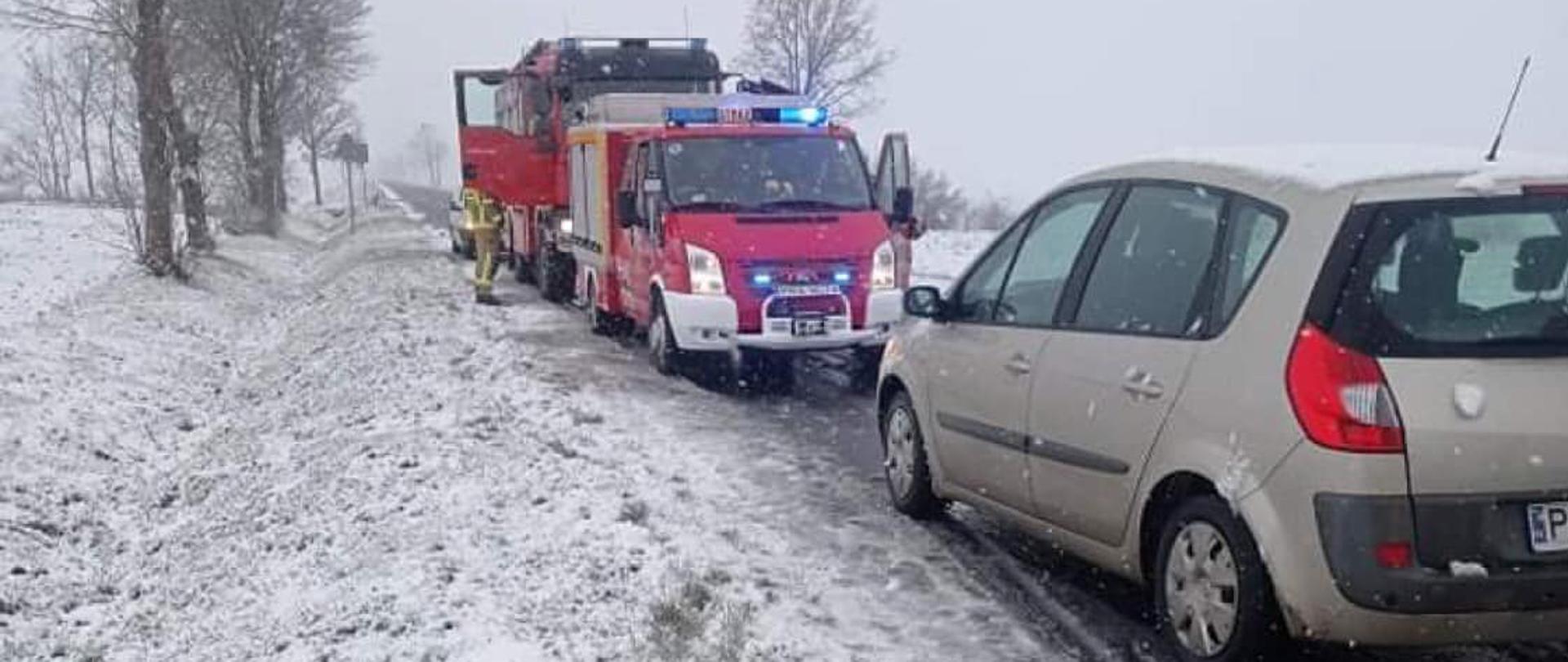 Zdjęcia przedstawia samochód osobowy. W tle stoją samochody pożarnicze.