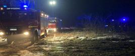 Na zdjęciu dwa samochody ratowniczo- gaśnicze na miejscu pożaru drewnianej stodoły.