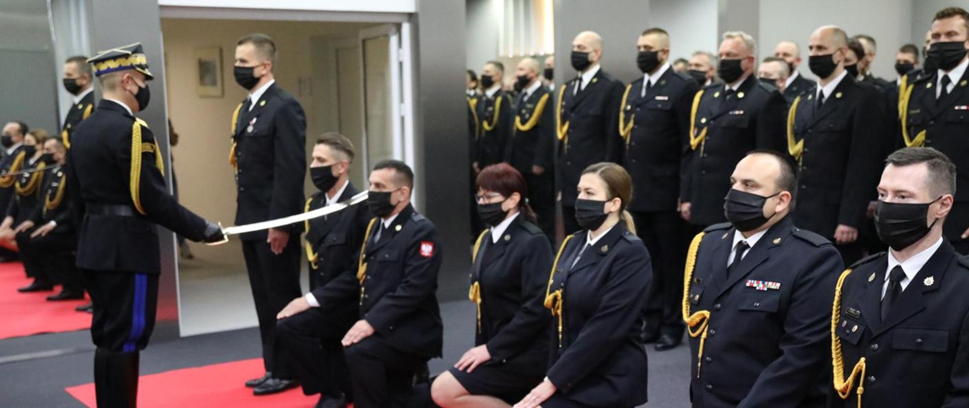 Komendant Główny PSP nadbrygadier Andrzej Bartkowiak i Zastępca Komendanta Głównego nadbrygadier Adam Konieczny w trakcie pasowania na oficera i wręczania aktu nadania pierwszego stopienia oficerskiego funkcjonariuszom PSP. W tle awansowani funkcjonariusze.