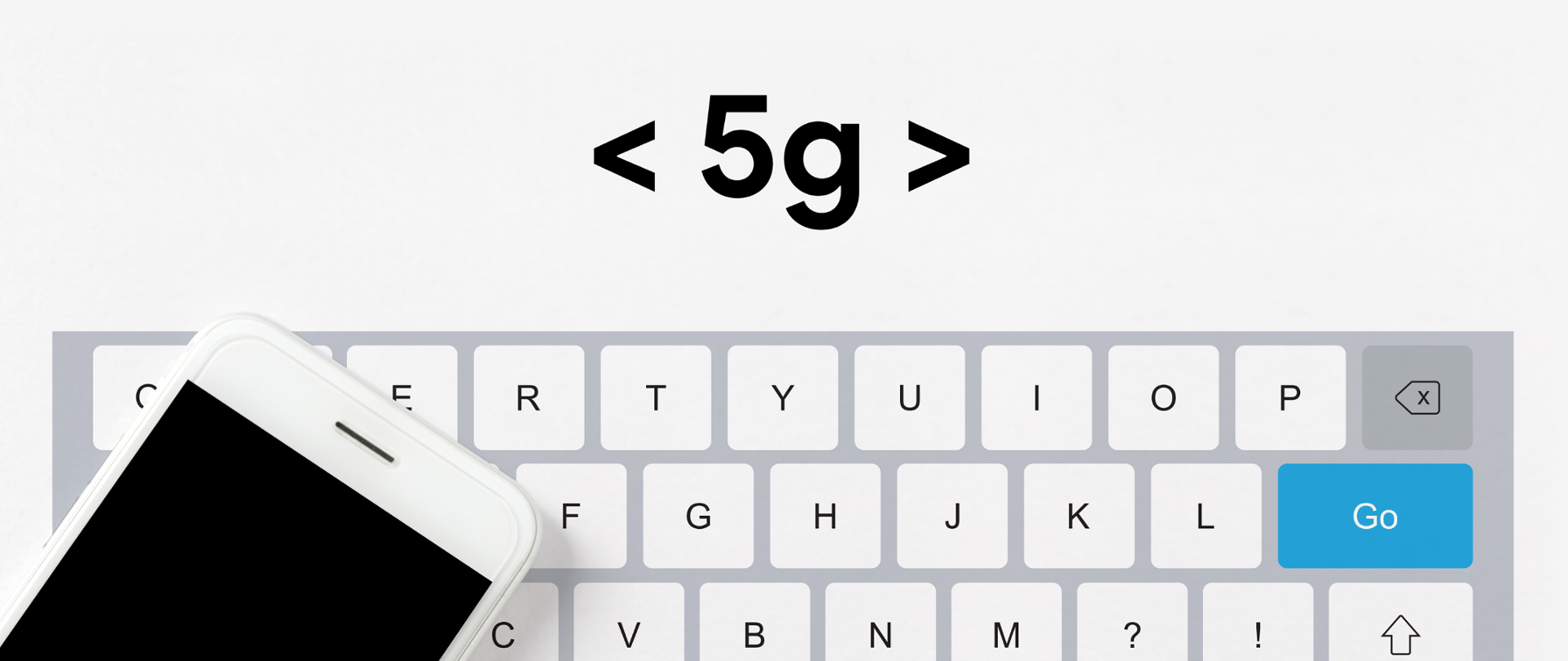 Klawiatura komputera, na niej telefon komórkowy oraz, powyżej, napis "5G"