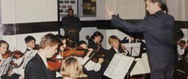 zdjęcie nauczyciela z orkiestrą uczniów