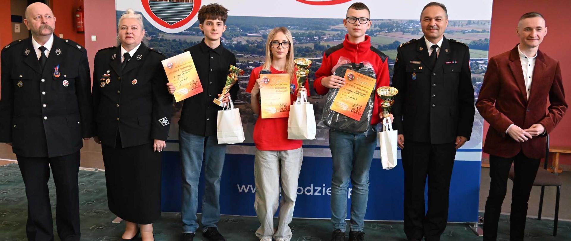 Eliminacje ogólnopolskiego turnieju wiedzy pożarniczej. Laureaci oraz strażacy stoją z nagrodami