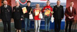Eliminacje ogólnopolskiego turnieju wiedzy pożarniczej. Laureaci oraz strażacy stoją z nagrodami
