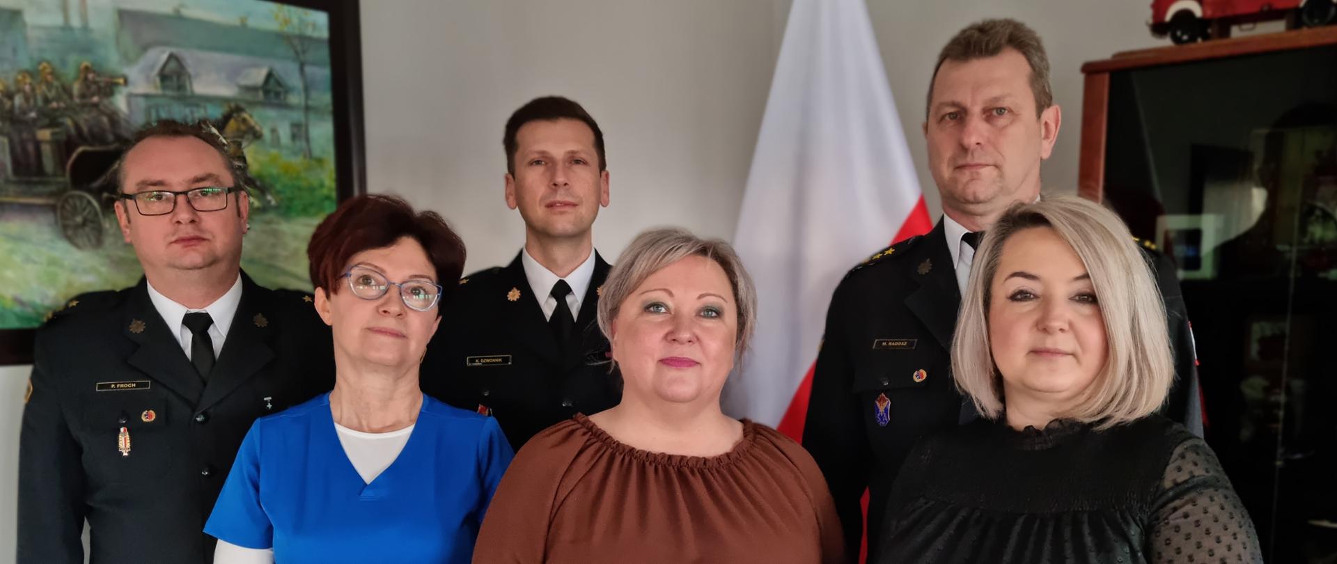 Na zdjęciu Komendant Miejski Państwowej Straży Pożarnej w Częstochowie wraz z zastępcami, przed nimi trzy pracownice otrzymujące gratulacje z okazji dnia korpusu służby cywilnej.