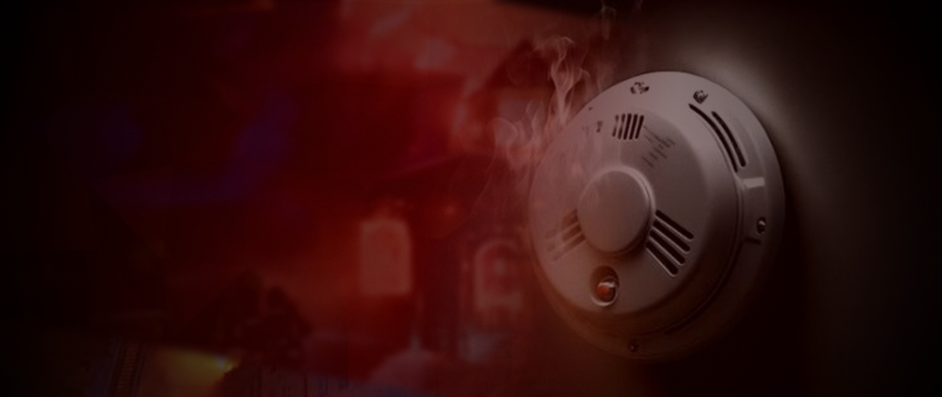 Grafika przedstawia czujkę dymu, w tle pożar budynku.