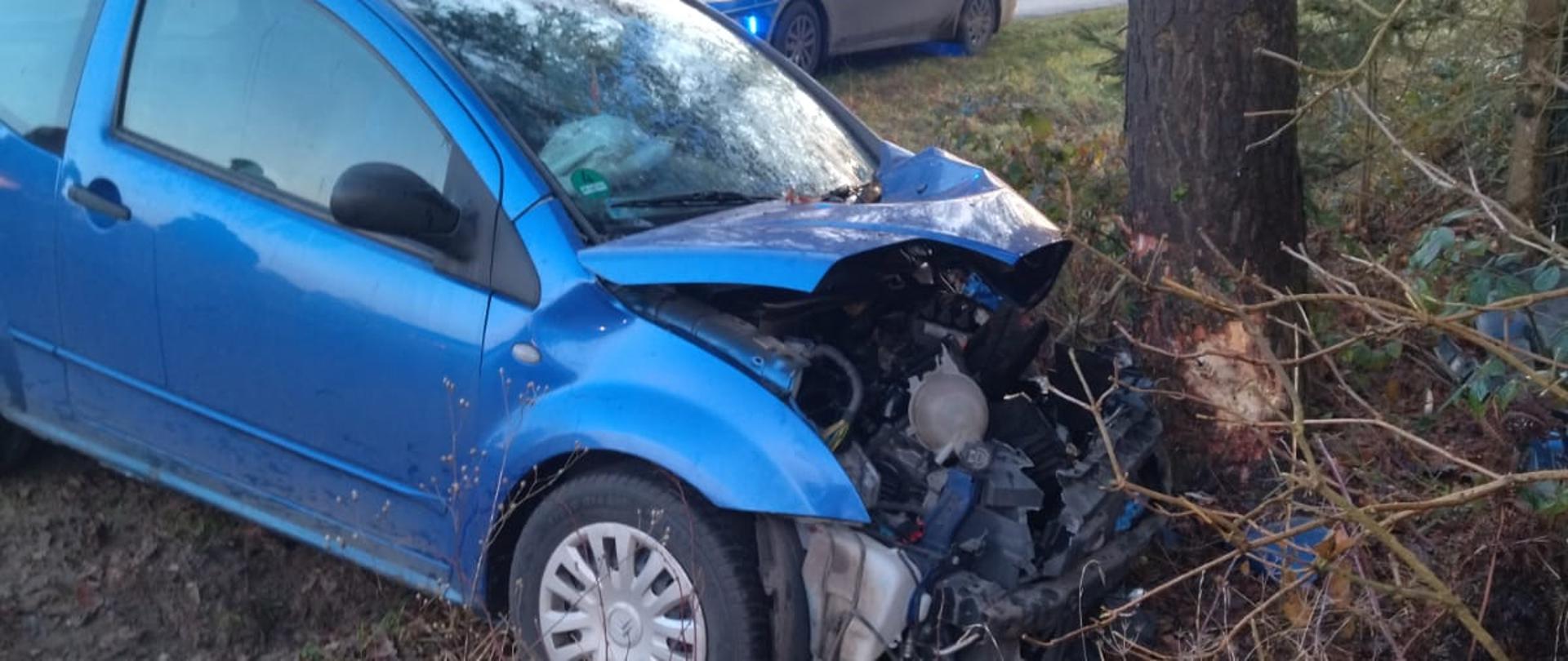Samochód osobowy koloru niebieskiego po uderzeniu w drzewo