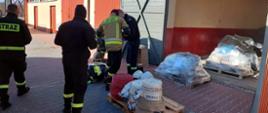Zdjęcie przedstawia strażaków pakujących sprzęt strażacki na palety