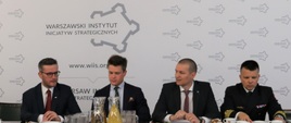 Grzegorz Witkowski (pierwszy z lewej), Podsekretarz Stanu w MGMiŻŚ wraz z trzema innymi uczestnikami spotkania. W tle logo Warszawskiego Instytutu Inicjatyw Strategicznych.