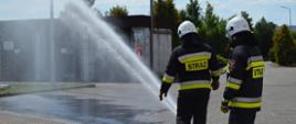 Zdjęcie przedstawia strażaków w trakcie ćwiczeń podczas schładzania butli z acetylenem