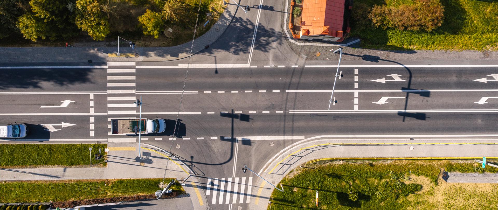 Tarcza zmodernizowanego skrzyżowania o nawierzchni asfaltowej. Z trzech stron wykonany jest chodnik. Pieszy ma do dyspozycji chodnik widoczny z lewej i dolnej strony fotografii.