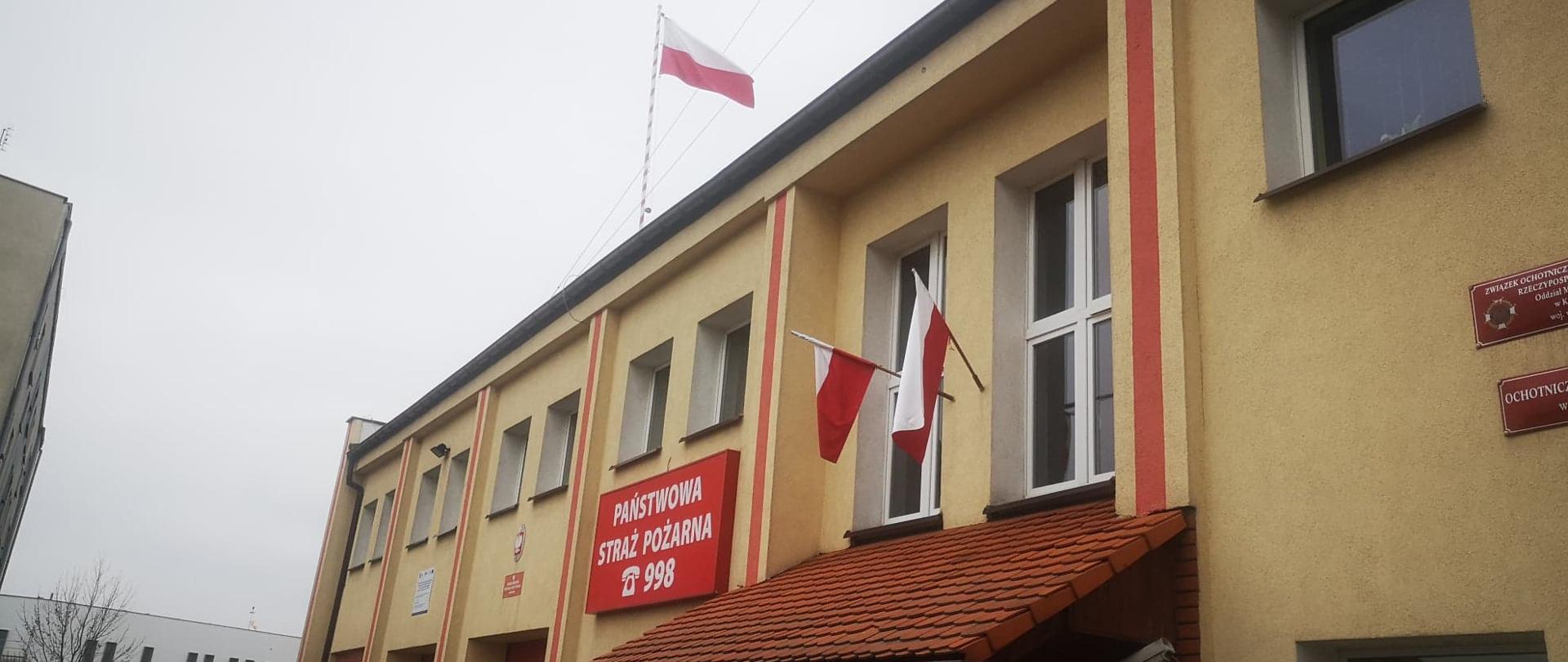 Wizerunek budynku KP PSP w Krotoszynie. Na dachu obiektu powiewa biało czerwona flaga.
