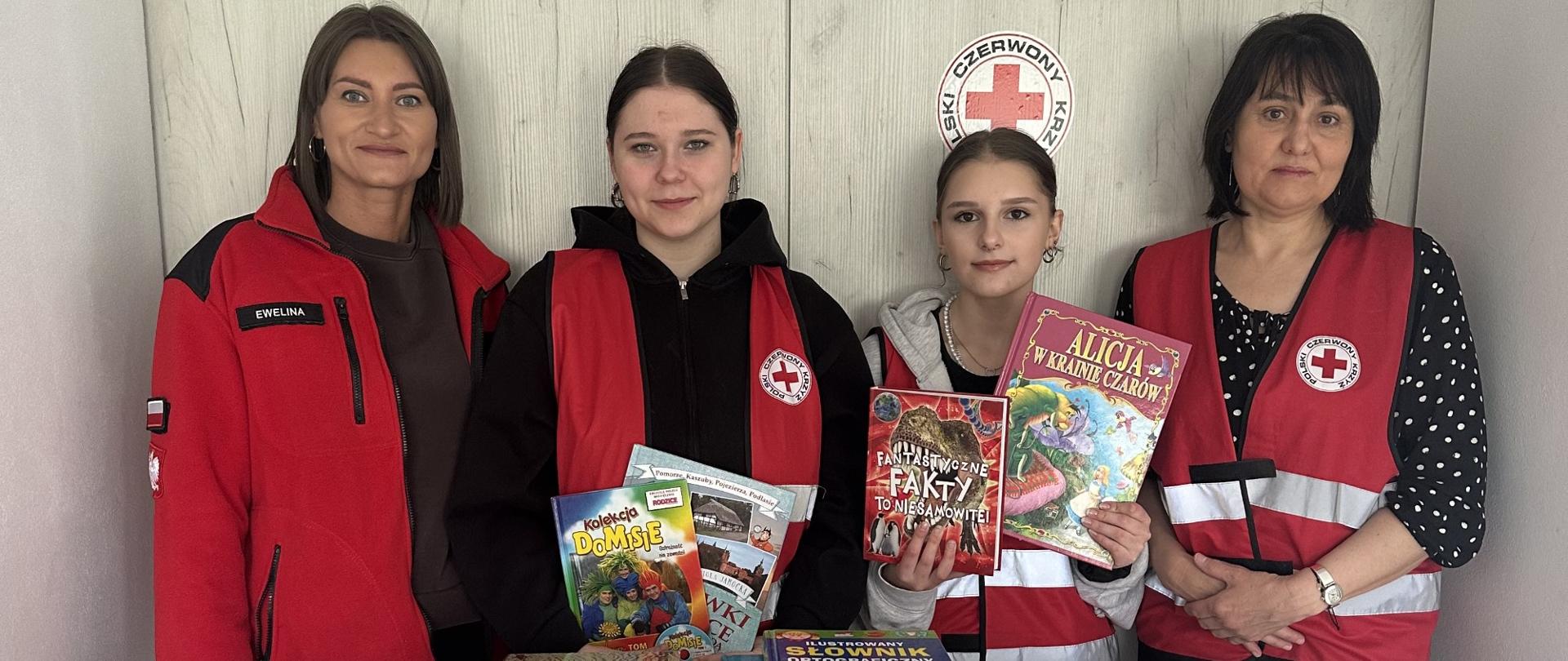 Uczestnicy akcji zbiórki książek stojący za stołem z zebranymi publikacjami.