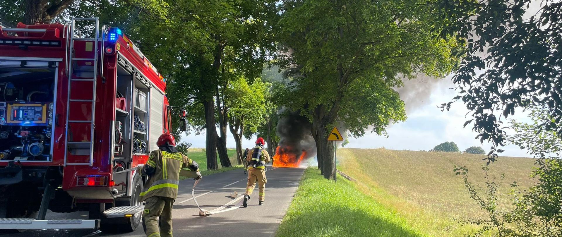 Strażacy gaszący palące się auto.