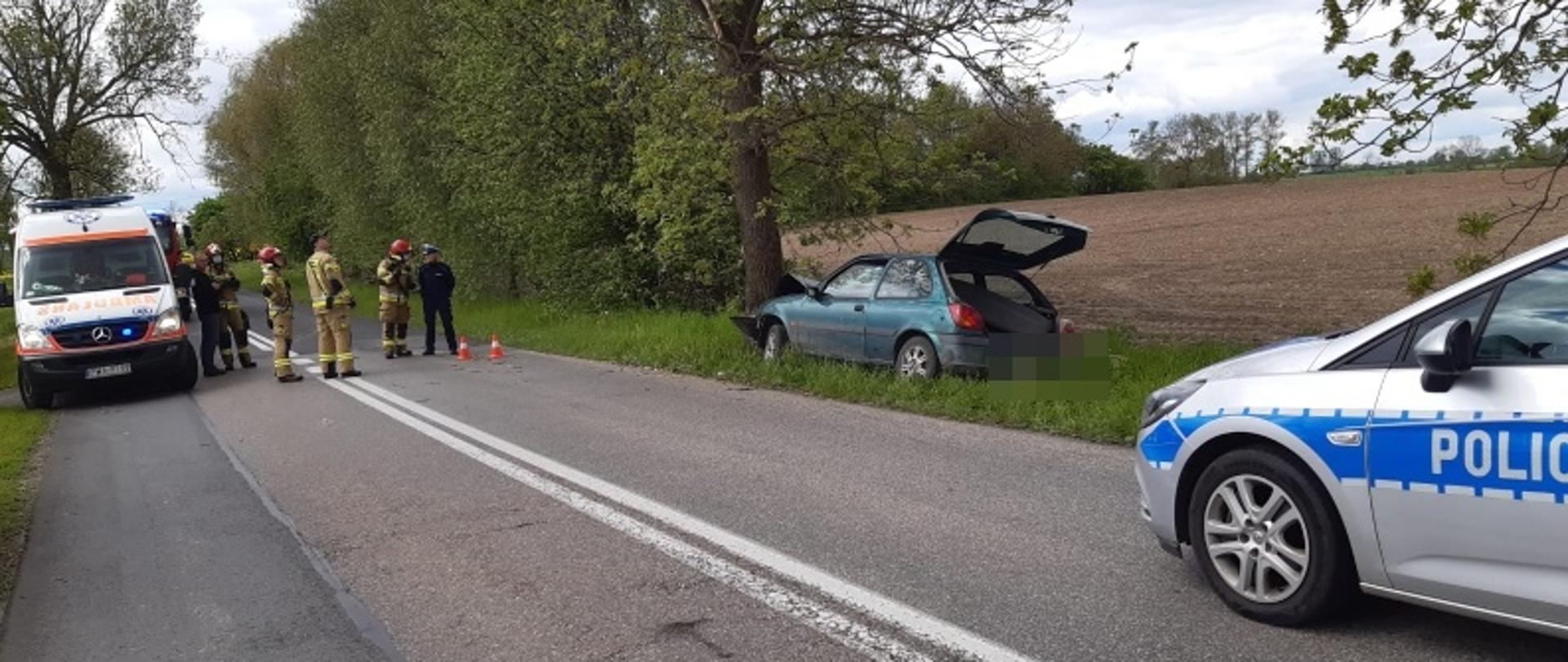 Na zdjęciu widać rozbity pojazd oraz pojazdy służb ratunkowych 