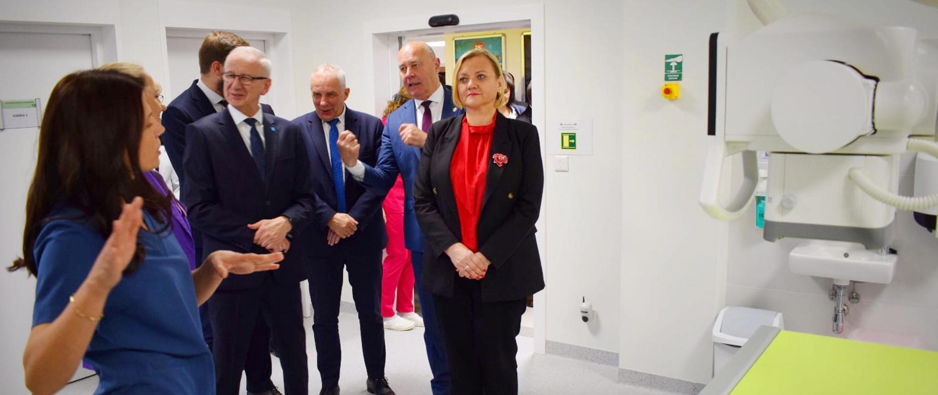 kilka osób stoi w sali gdzie znajduje się tomograf komputerowy