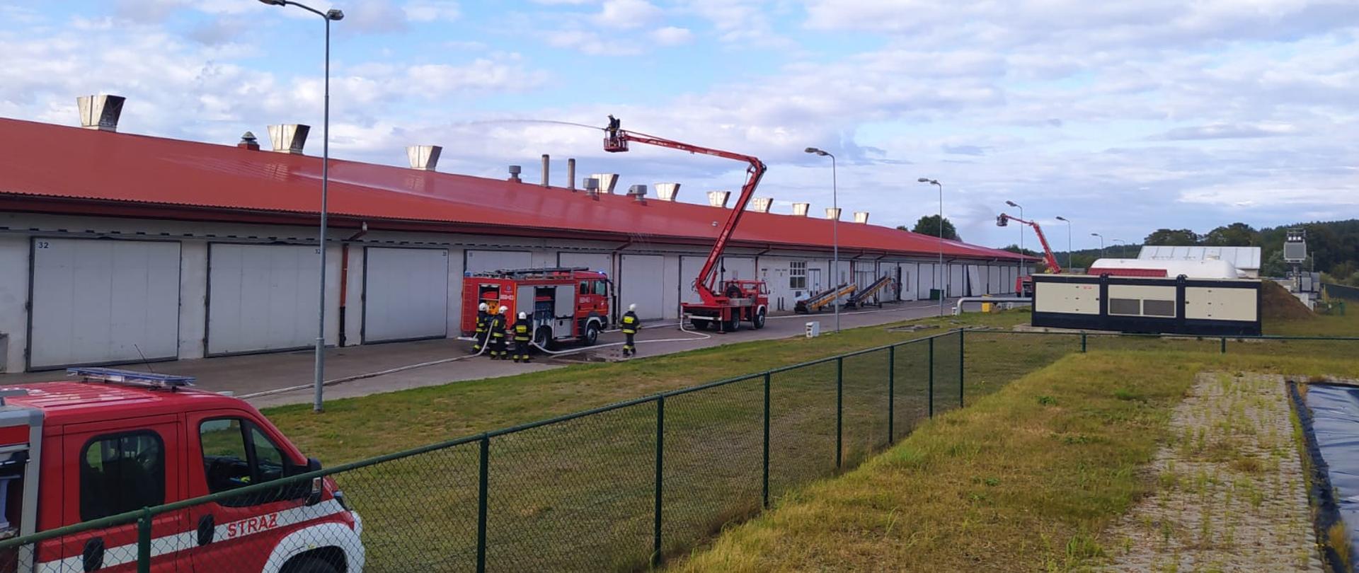 Na zdjęciu widoczne są samochody strażackie w oddali widać pracujące podnośniki strażackie.