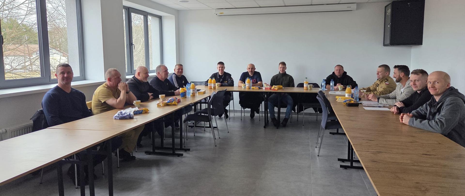 W sali konferencyjnej przy stole siedzą mężczyźni