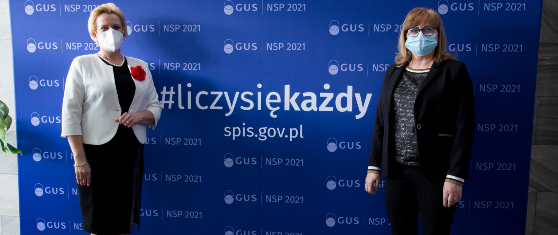 Po lewej stronie wicewojewoda opolski, ubrana w czarną sukienkę do kolan i biały żakiet, w którego klapie ma wpięty czerwony kwiat. Obok stoi kobieta - dyrektor opolskiego US ubrana w ciemny garnitur, na twarzy ma okulary optyczne. Obie panie stoją na tle granatowej ścianki, długości 3 metrów, z napisem Liczy się Każdy 