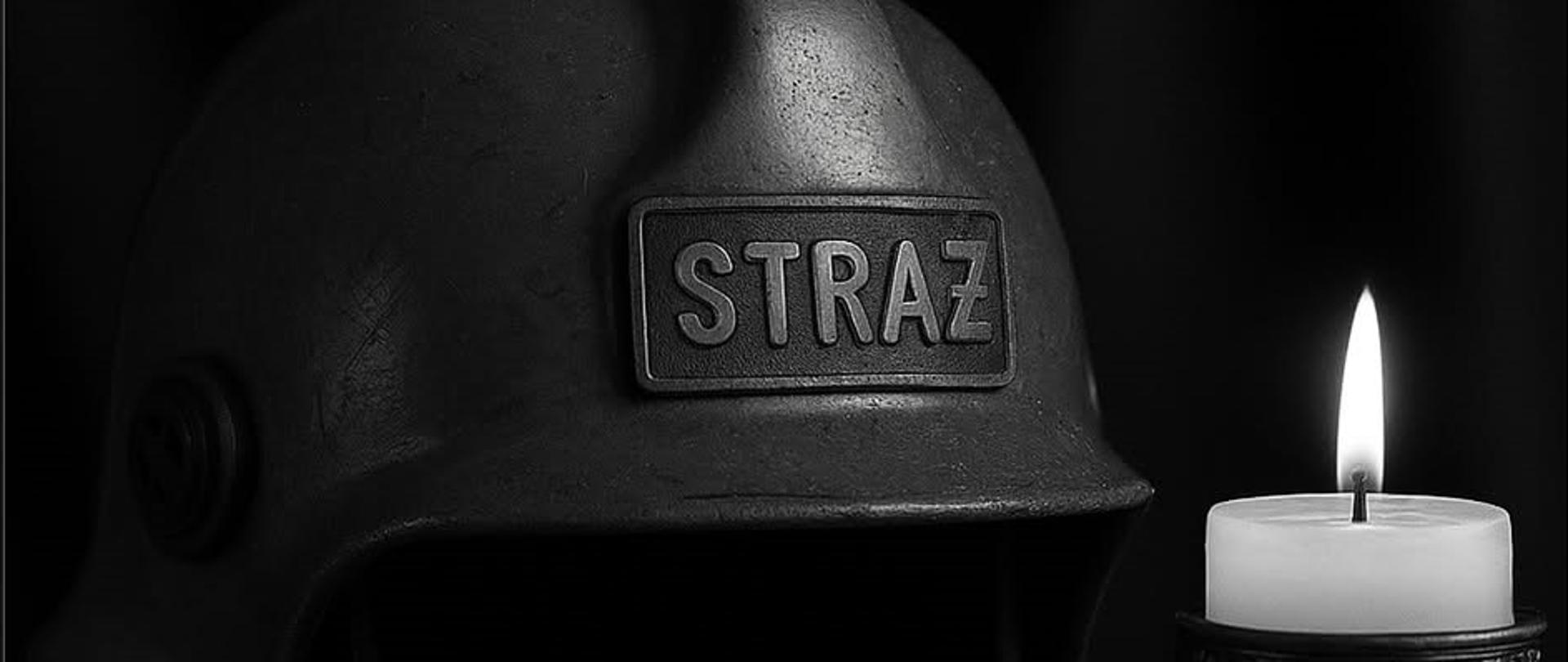 Czarno białe zdjęcie przedstawiające hełm z napisem straż oraz zapaloną świecę znajdującą się z prawej strony zdjęcia.