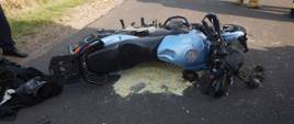 Zdjęcie przedstawia przewrócony na prawy bok motocykl, po zderzeniu z innym motocyklem. Motocykl znajduje się na jezdni.