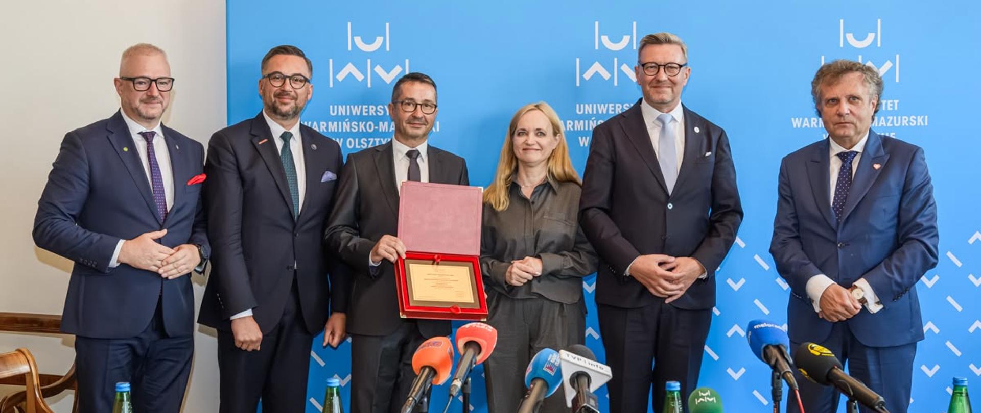 Na zdjęciu wiceminister Jacek Karnowski na briefingu prasowym na Uniwersytecie Warmińsko-Mazurskim w Olsztynie w towarzystwie innych uczestników spotkania