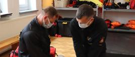 Dwóch strażaków klęczy nad manekinem i ćwiczy wykonywanie resuscytacji krążeniowo-oddechowej