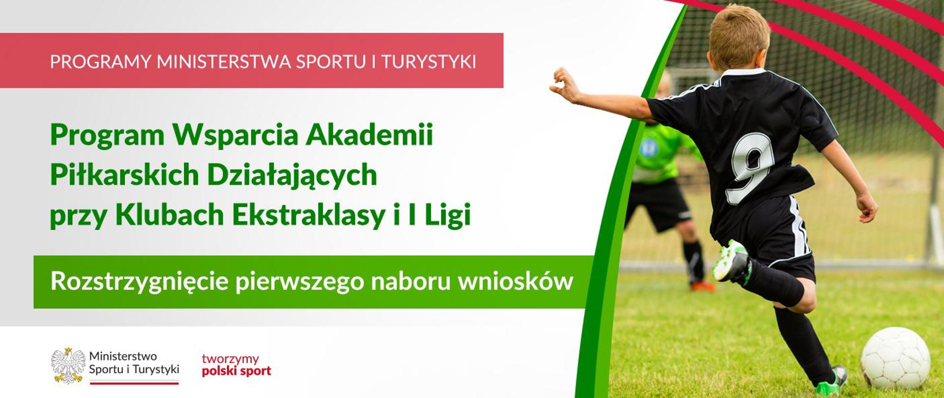 Grafika. Z lewej strony od góry napisy: (1) na czerwonym tle biały napis dużymi literami: PROGRAMY MINISTERSTWA SPORTU I TURYSTYKI, (2) na jasnym tle zielonymi literami: Program Wsparcia Akademii Piłkarskich Działających przy Klubach Ekstraklasy i I Ligi, (3) na zielonym tle białymi literami: Rozstrzygnięcie pierwszego naboru wniosków. Na dole na białym pasku logotypy MSiT oraz tworzymy polski sport. Z prawej strony zdjęcie. Boisko piłkarskie. Chłopiec w czarnym stroju piłkarskim z białymi wstawkami z numerem 9 na plecach kopie piłkę w kierunku bramki. W tle bramka, w niej stoi młody bramkarz.