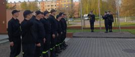 Zdjęcie przedstawia uroczyste podniesienie flagi państwowej przez poczet flagowy oraz zmiany służbowe przed Komendą Powiatową PSP w Wałczu