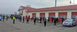 Zdjęcie przedstawia plac Komendy Powiatowej Państwowej Straży Pożarnej w Radziejowie na którym ćwiczą strażacy OSP wspólnie z Policjantami z Komendy Powiatowej Policji z Radziejowa. Na zdjęciu również po prawej stronie stoi radiowóz policyjny.