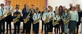 Zdjęcie przedstawiające wszystkich wykonawców koncertu muzyki saksofonowej w auli szkoły.