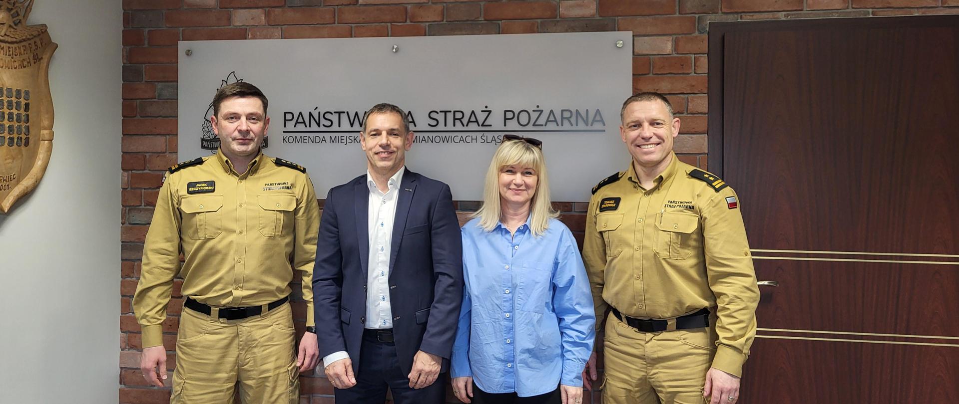 Na pierwszym planie na dolnym środku położony jest automatyczny zewnętrzny defibrylator. Za nim stoją Komendanci Miejscy PSP w Siemianowicach Śląskich wraz z przedstawicielami firmy Setmil. 