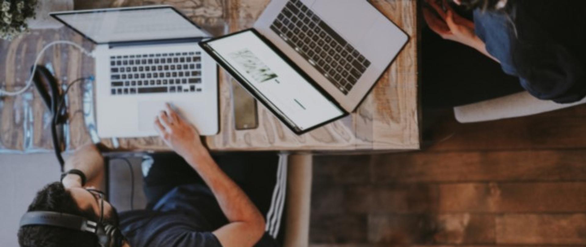 Osoby pracują przy komputerze, przy jednym stole