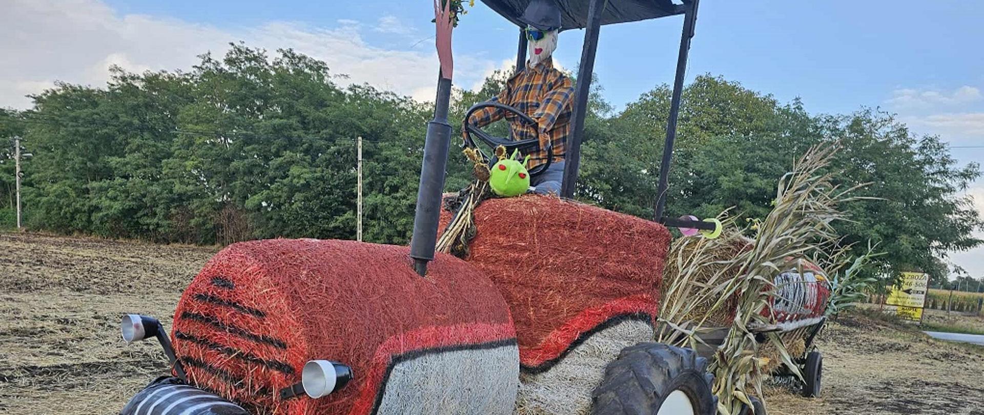 Pesty siedzący na witaczu dożynkowym w formie ciągnika rolniczego na jednej z dróg powiatu kazimierskiego