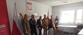 Zdjęcie przedstawia Komendanta Powiatowego PSP w Człuchowie, członków komisji egzaminacyjnej oraz sponsorów podczas wręczania nagród uczestnikom konkursu. W tle godło i flaga państwowa.