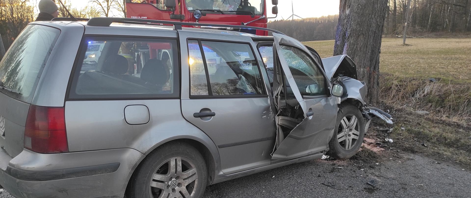 Srebrny samochód osobowy kombi, za nim czerwony samochód strażacki