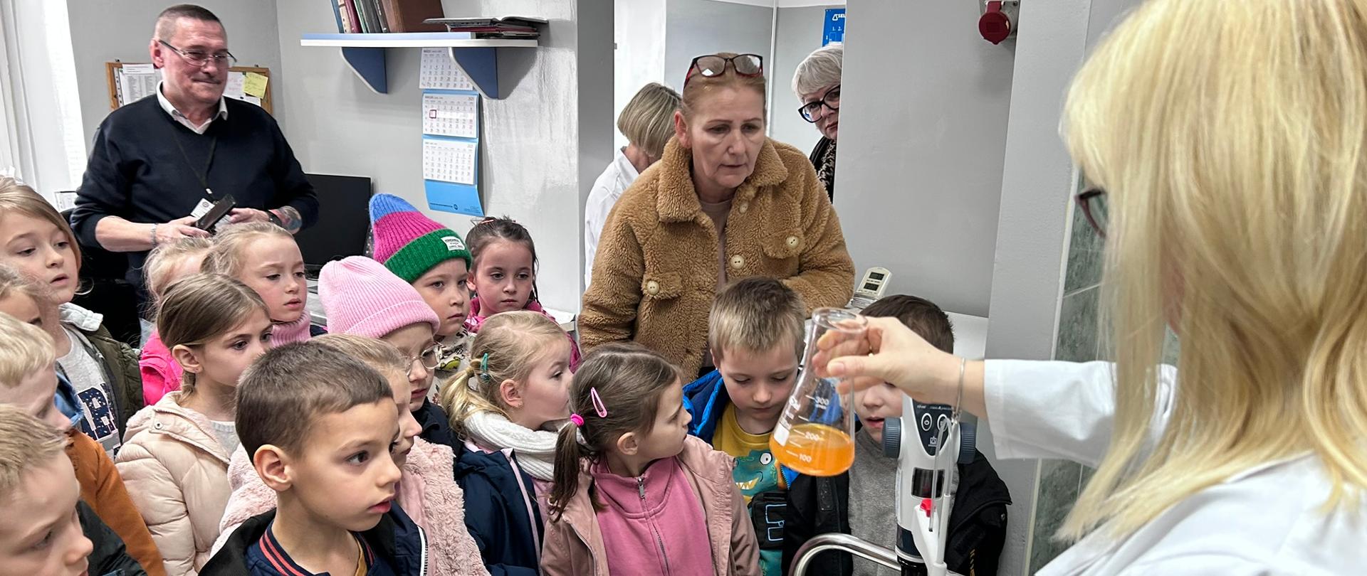 Pracownik laboratorium PSSE pokazuje dzieciom jedno z badań demonstracyjnych