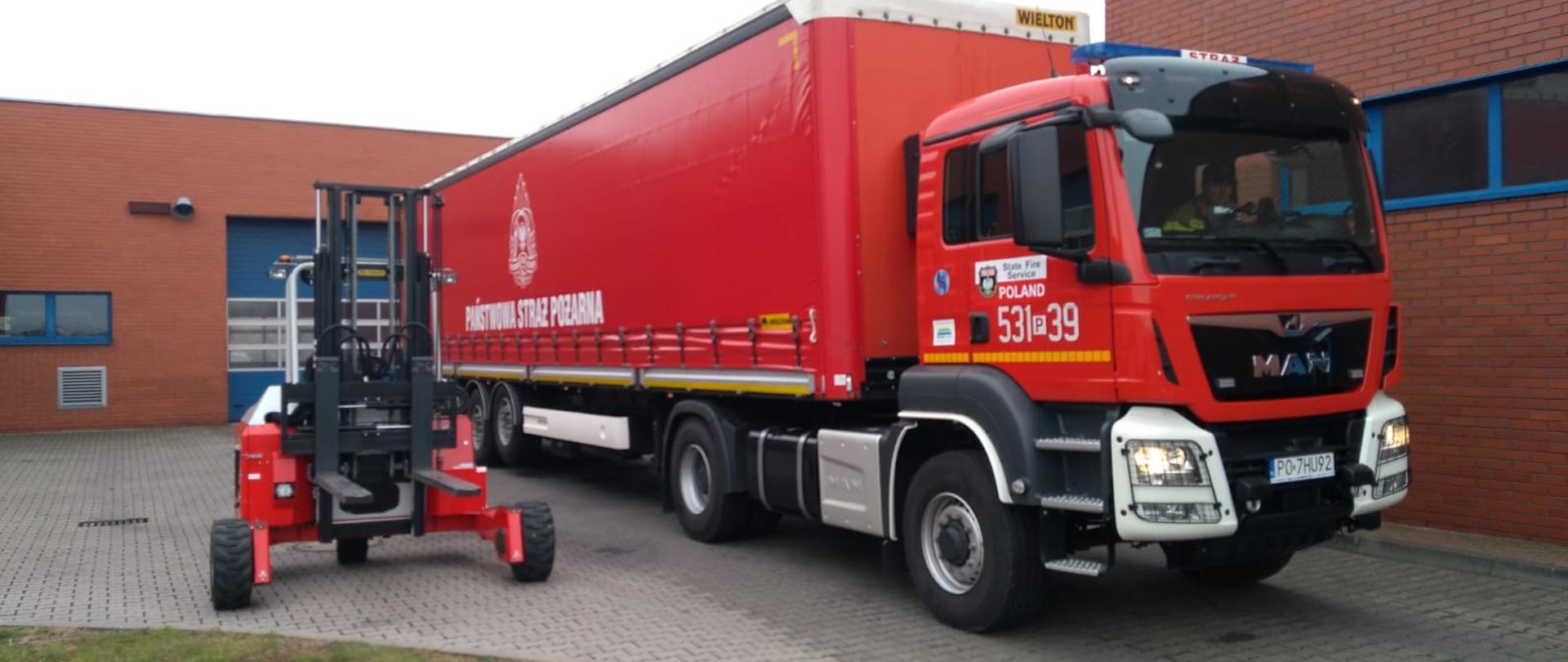 Specjalistyczny wózek widłowy, samochód strażacki, czerwona naczepa z logo PSP.