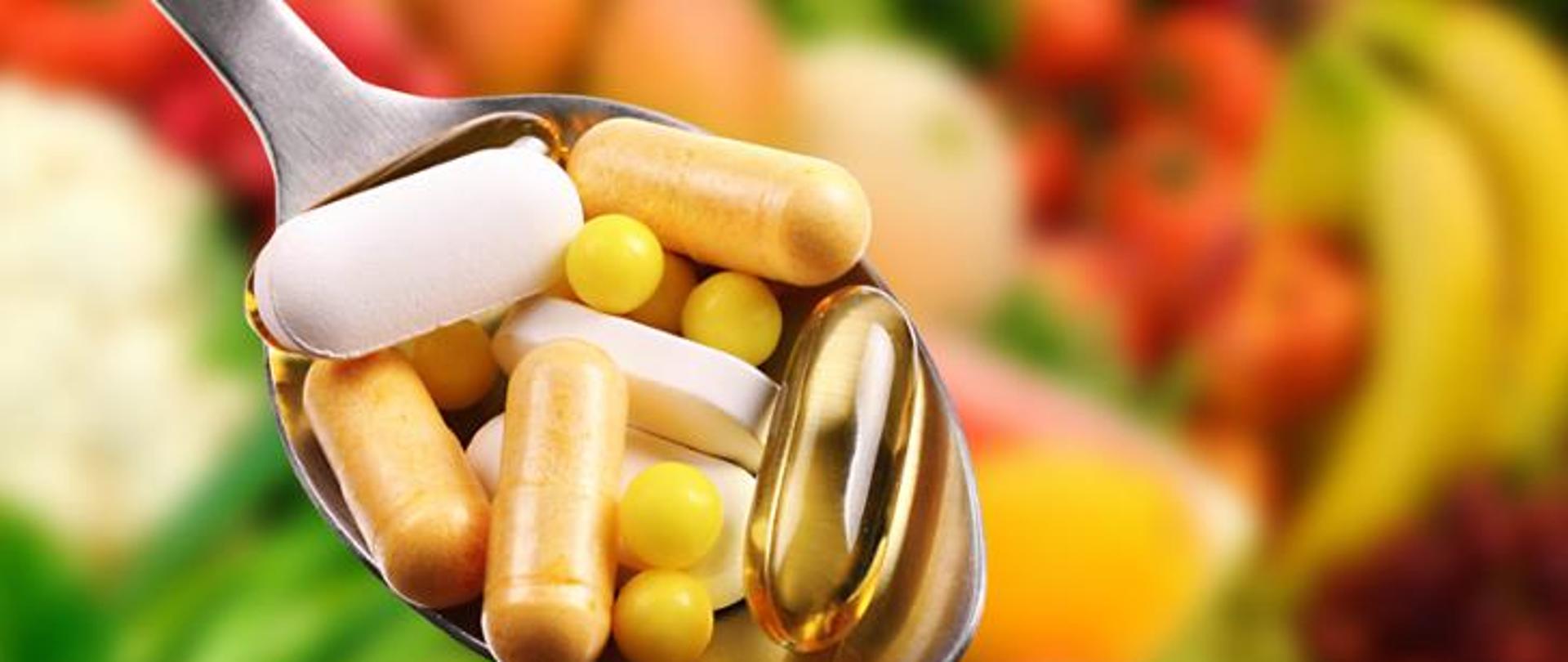 Na zdjęciu znajduje się łyżka na której są kolorowe tabletki