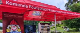 Stoisko pleszewskiej straży podczas festiwalu lasu. Mobilny symulator zagrożeń oraz baner straży pożarnej.