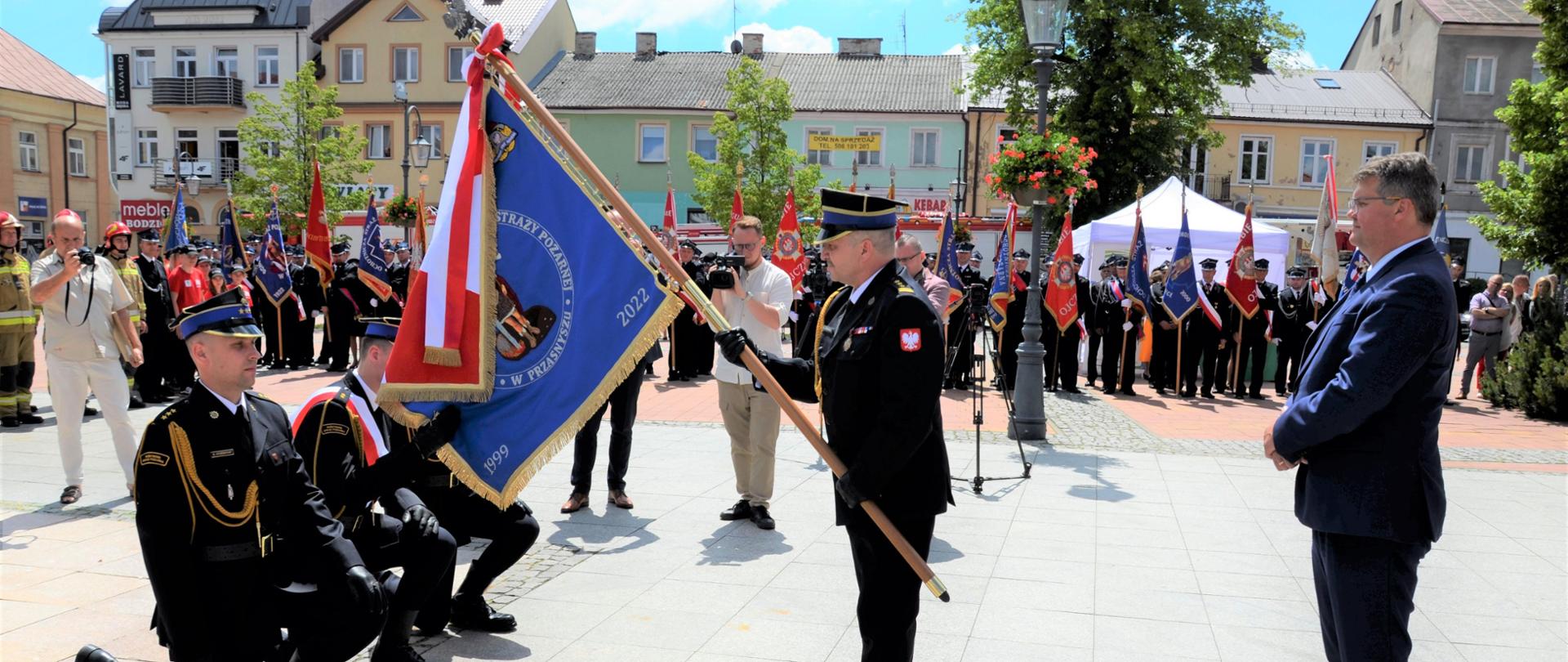 11 czerwca 2022 roku na Rynku Miejskim w Przasnyszu odbyły się Powiatowe Obchody Dnia Strażaka, połączone z nadaniem sztandaru Komendzie Powiatowej Państwowej Straży Pożarnej w Przasnyszu w jubileusz 30-lecia powstania Państwowej Straży Pożarnej.
Uroczystość rozpoczęła się Mszą Świętą w intencji strażaków w Kościele Św. Wojciecha, którą sprawował kapelan strażaków powiatu przasnyskiego Ojciec dh Wiesław Wiśniewski w asyście, kapelana mazowieckich strażaków ks. mł.bryg. Jerzego Sieńkowskiego oraz księży proboszczów z parafii powiatu przasnyskiego.
Po mszy nastąpił przemarsz pododdziałów na Rynek Miejski w Przasnyszu gdzie odbył się uroczysty apel, zapoczątkowany złożeniem meldunku przez dowódcę uroczystości kpt. Piotra Kuligowskiego Panu Maciejowi Wąsikowi – Sekretarzowi Stanu w Ministerstwie Spraw Wewnętrznych i Administracji, który dokonał przeglądu pododdziałów i przywitał się z pocztami sztandarowymi. Następnie podniesiono flagę państwową i odegrano Mazurek Dąbrowskiego Hymn Polski.
Dla strażaków z Przasnysza było to wyjątkowe święto ponieważ dla Komendy Powiatowej Państwowej Straży Pożarnej w Przasnyszu został nadany i wręczony Sztandar ufundowany przez społeczność lokalną, który jest wyrazem podziękowania strażakom i pracownikom cywilnym za ich służbę oraz pracę na rzecz poprawy bezpieczeństwa na terenie powiatu przasnyskiego. Uroczystego przekazania sztandaru dokonał Przewodniczący Społecznego Komitetu Fundatorów Sztandaru- Starosta Przasnyski Krzysztof Bieńkowski, Sekretarz Stanu w Ministerstwie Spraw Wewnętrznych i Administracji Pan Maciej Wąsik oraz Komendant Powiatowy Państwowej Straży Pożarnej w Przasnyszu st. bryg. Waldemar Białczak. Poświęcenia sztandaru dokonał kapelan strażaków powiatu przasnyskiego Ojciec dh Wiesław Wiśniewski CP i kapelan mazowieckich strażaków ks. mł. bryg. Jerzy Sieńkowski.
Z okazji święta Dnia Strażaka wręczono odznaczenia, akty nadania wyższych stopni służbowych oraz medale i dyplomy okolicznościowe z okazji 30-lecia Państwowej Straży Pożarnej:
• „ Brązowym Krzyżem Zasługi” odznaczone zostały 3 osoby;
• „Srebrną odznaką zasłużony dla ochrony przeciwpożarowej” odznaczona została 1 osoba;
• „ Brązowa odznaką zasłużony dla ochrony przeciwpożarowej” odznaczone zostały 3 osoby
• „ Złotym Znakiem Związku OSP RP” odznaczona została 1 osoba;
• „Złotym Medalem Za Zasługi Dla Pożarnictwa” odznaczonych zostało 7 osób
• „ Srebrnym Medalem Za Zasługi Dla Pożarnictwa” odznaczonych zostało 5 osób;
• „ Brązowym Medalem Za Zasługi Dla Pożarnictwa” odznaczonych zostało 7 osób;
Awans na wyższy stopień służbowy odebrało 14 funkcjonariuszy Komendy Powiatowej PSP w Przasnyszu
Dyplomem Komendanta Głównego Państwowej Straży Pożarnej z okazji 30-lecia Państwowej Straży Pożarnej, wyróżnionych zostało 2 strażaków, natomiast medalem Okolicznościowym Mazowieckiego Komendanta Wojewódzkiego Państwowej Straży Pożarnej wyróżnionych zostało 10 osób.
Mazowiecki Komendant Wojewódzki Państwowej Straży Pożarnej nadbryg. Jarosław Nowosielski w dowód uznania za szczególne zaangażowanie na rzecz ochrony przeciwpożarowej powiatu przasnyskiego wyróżnił 10 druhów listami gratulacyjnymi.
Podczas uroczystości st. bryg. Waldemar Białczak Komendant Powiatowy Państwowej Straży Pożarnej w Przasnyszu został odznaczony przez Zarząd Główny NSZZ Policjantów Krzyżem Niepodległości Klasy I z Gwiazdą, a z rąk Sekretarza Stanu w Ministerstwie Spraw Wewnętrznych i Administracji Pana Macieja Wąsika odebrał promesę na remont budynku Jednostki Ratowniczo-Gaśniczej.
Obchody Powiatowego Dnia Strażaka w Przasnyszu swoją obecnością zaszczycili m.in.: Pan Maciej Wąsik Sekretarz Stanu w Ministerstwie Spraw Wewnętrznych i Administracji, Pan Rafał Romanowski Sekretarz Stanu w Ministerstwie Rolnictwa, Pani Anna Ewa Cicholska Poseł na Sejm, nadbryg. Jarosław Nowosielski Mazowiecki Komendant Wojewódzki Państwowej Straży Pożarnej, parlamentarzyści, przedstawiciele władz wojewódzkich, przedstawiciele władz samorządowych, przedstawiciele służb mundurowych, przedstawiciele jednostek Ochotniczych Straży Pożarnych, lokalna społeczność.
Goście uczestniczący w uroczystości składali gratulacje odznaczonym, awansowanym i wyróżnionym strażakom oraz osobom zaangażowanym w sprawy pożarnictwa, doceniając ciężką pracę strażaków.
Koło Gospodyń z Węgry ze wsparciem Ministerstwa Rolnictwa oraz Krajowego Ośrodka Wsparcia Rolnictwa zorganizowało część gastronomiczną uroczystości.
Opracował: kpt. Piotr Kuligowsk.i
Zdjęcia: asp. Rafał Sekuna.
