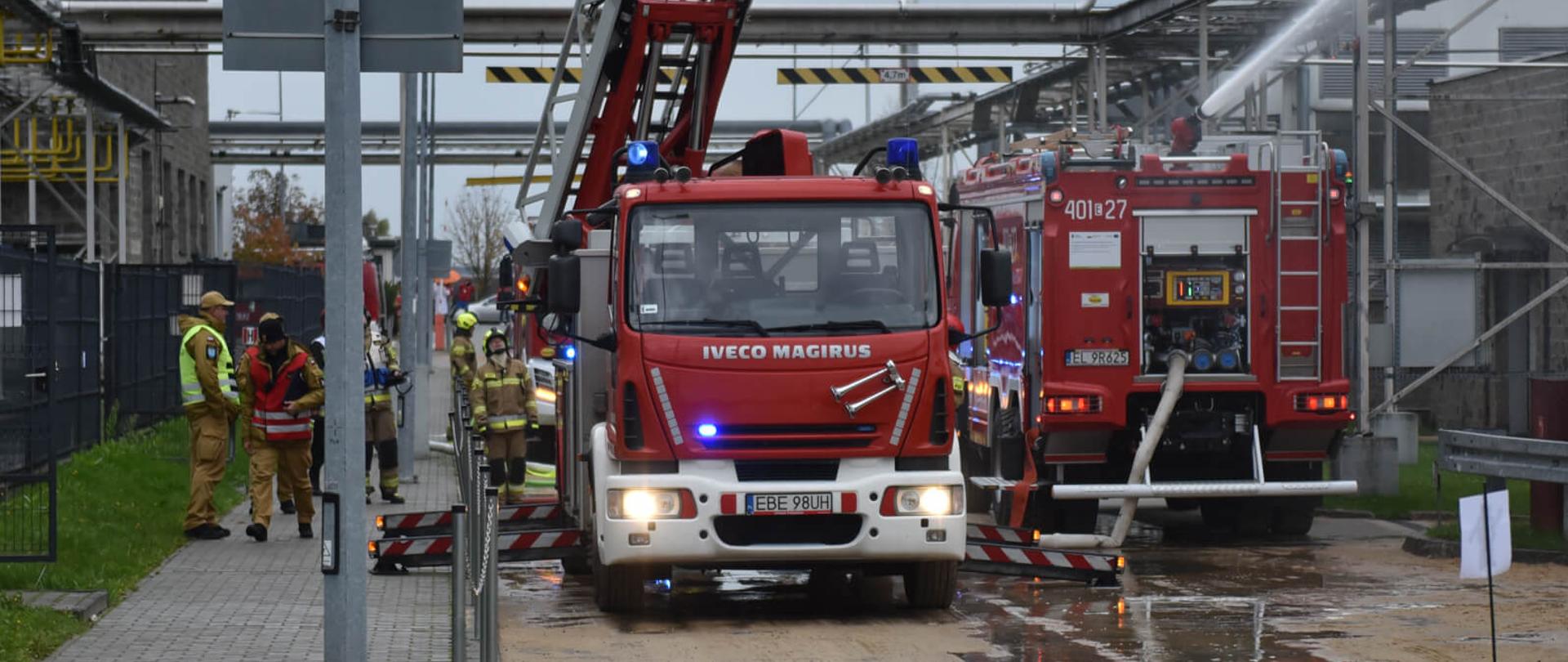 drabina mechaniczne oraz samochód gaśniczy oraz strażacy w czasie ćwiczeń w zakładzie produkcyjnym