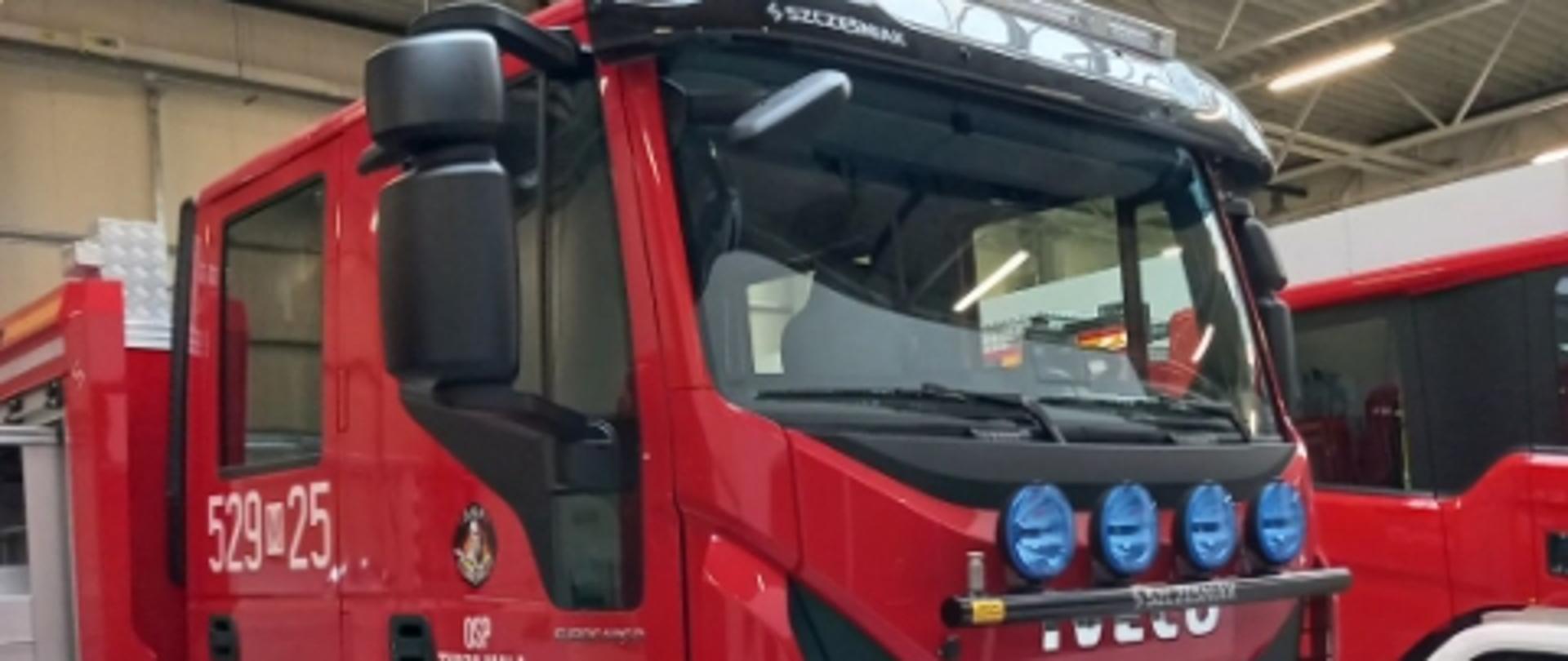 W hali magazynowej stoją zaparkowane pojazdy pożarnicze. Na głównym planie, auto, IVECO. 