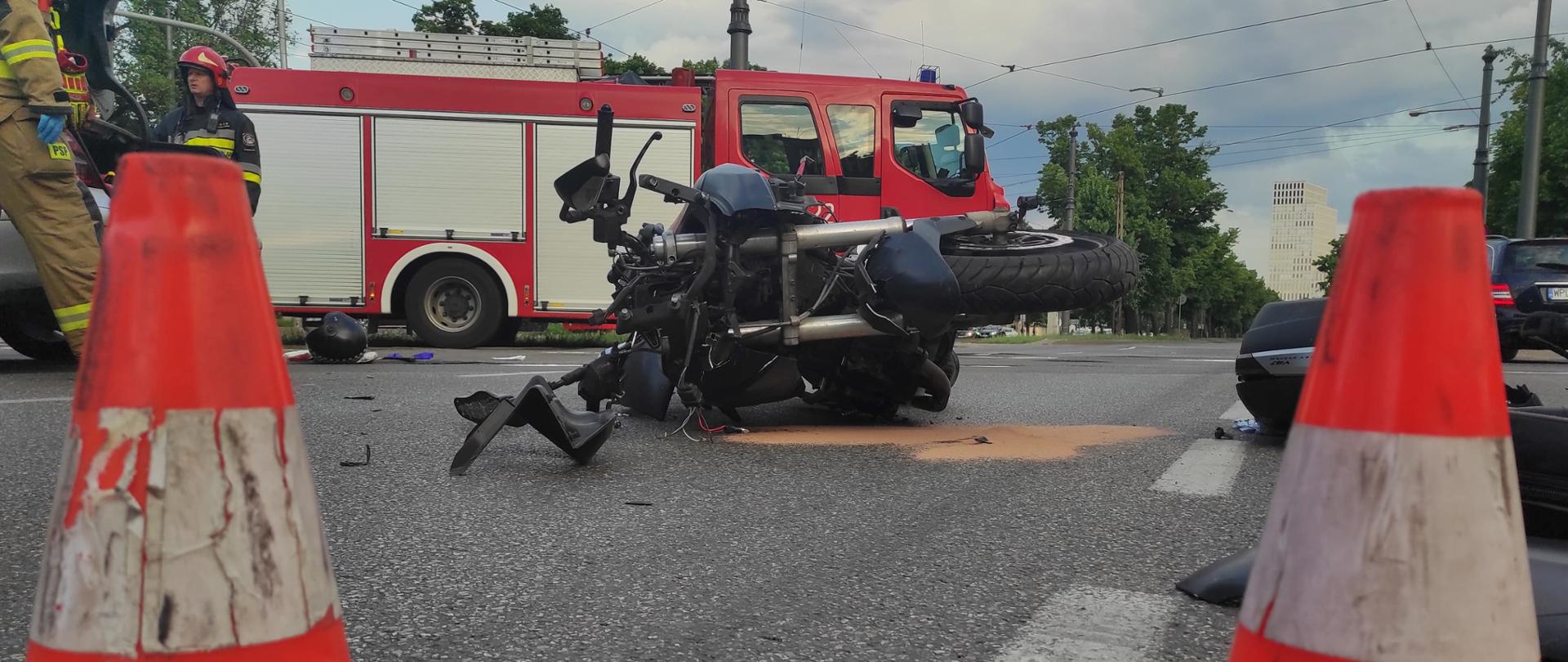 Na zdjęciu widoczne stożki ostrzegawcze, ukoszony motocykl oraz wóz straży pożarnej.